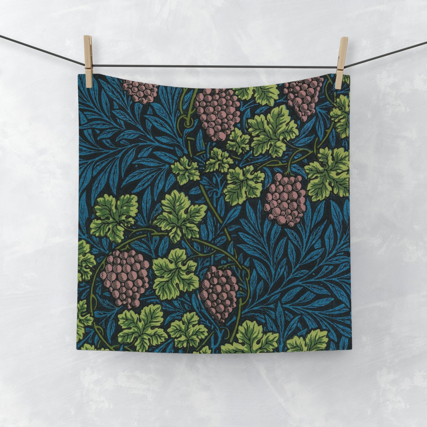 A white washcloth with a floral pattern inspired by William Morris, featuring green leaves and pink grapes.