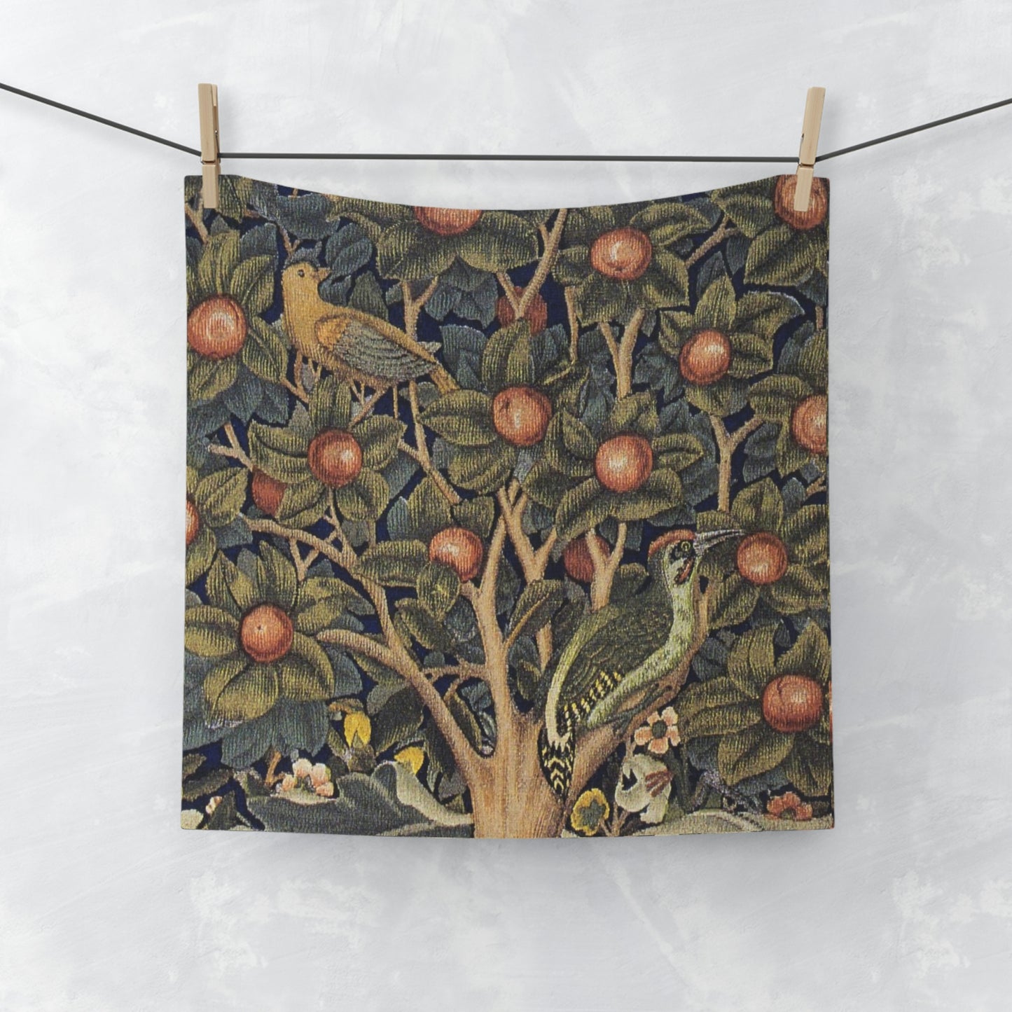 A washcloth with a floral pattern inspired by William Morris, featuring birds and woodpeckers amidst green leaves and red fruits.