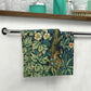 A white washcloth with a floral pattern inspired by William Morris, featuring an illustration of squirrels and leaves.